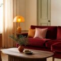 Salon chaleureux aux couleurs 2026 avec canapé rouge profond et coussins ambre