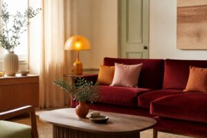 Salon chaleureux aux couleurs 2026 avec canapé rouge profond et coussins ambre
