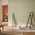 Mur couvert d'un papier peint intisse a motif geometrique vert sauge avec materiel de pose