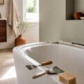 Salle de bains avec baignoire blanche et ancien joint silicone noirci à retirer