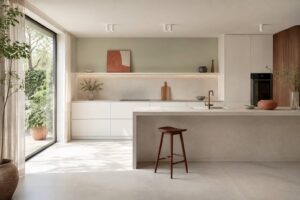 Cuisine contemporaine lumineuse au sol en grès cérame effet béton avec fenêtre et plan de travail