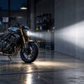 Moto aux feux allumes eclairant un mur dans un atelier sobre